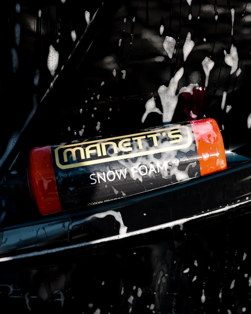 Manetts Snow Foam bottle resting in foam on a black vehicle, Dallas